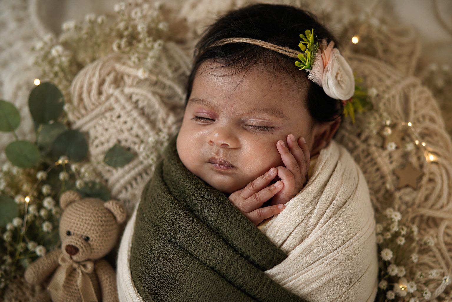 Smiling baby resting on a purple blanket surrounded by pink peonies and fairy lights