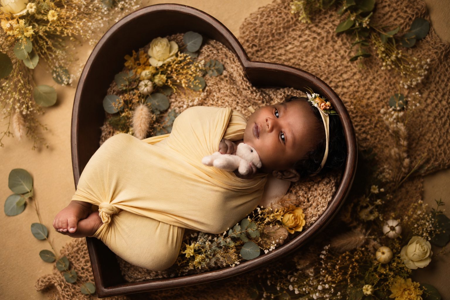 Sleeping newborn in purple bonnet surrounded by dried lavender and daisies