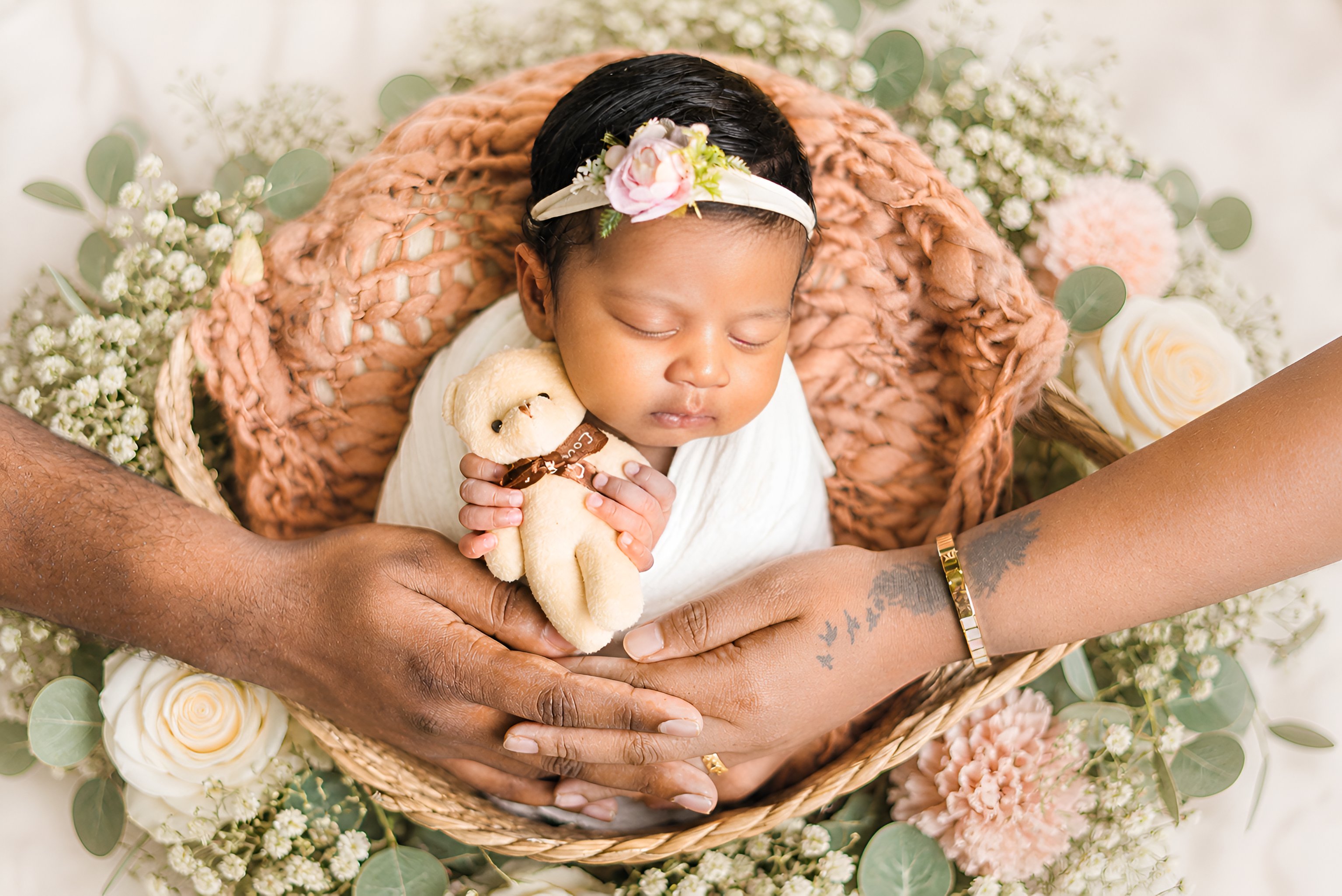 Family photographer Dubai — parent hands surrounding newborn baby